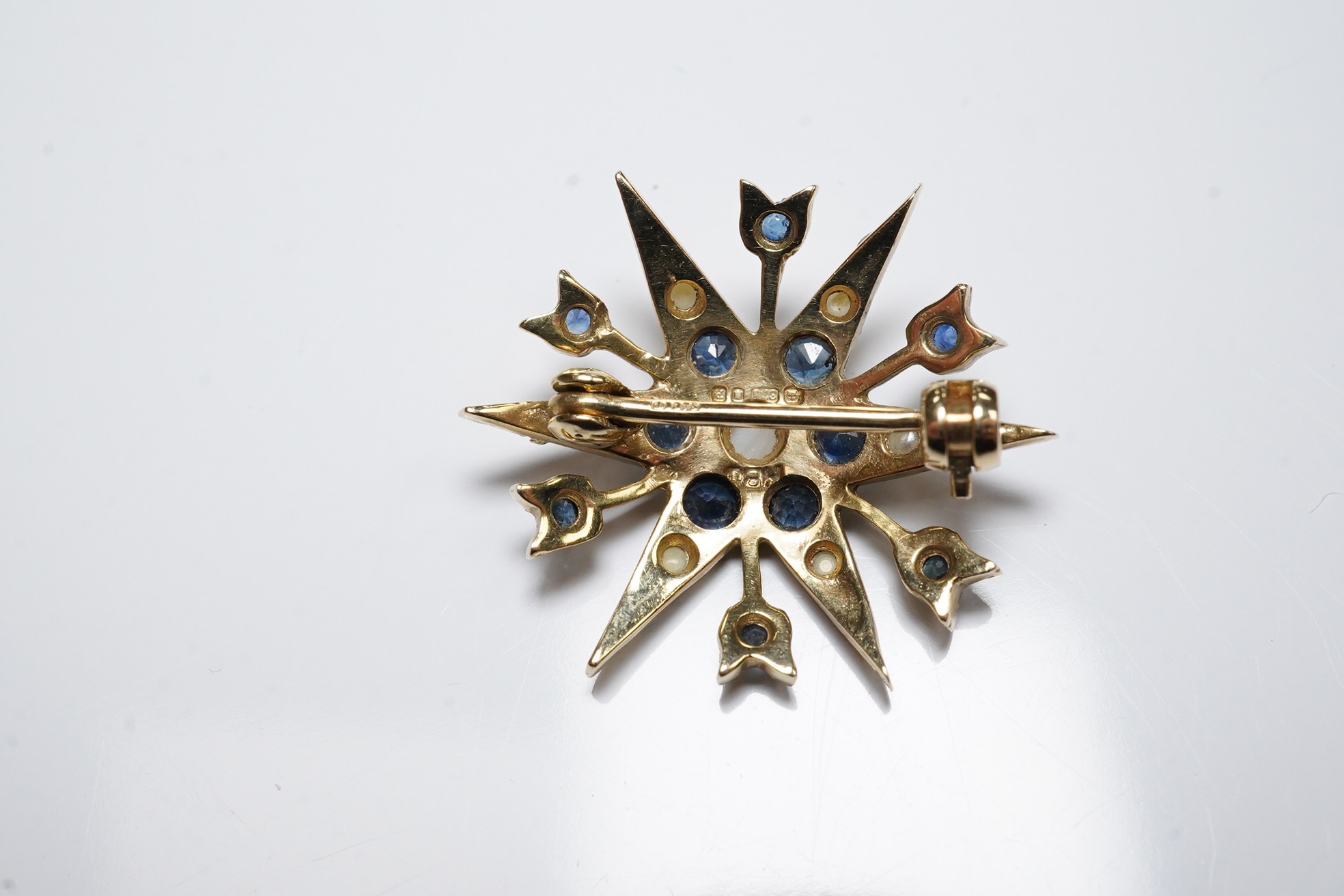 A modern Edwardian style 9ct gold, sapphire and graduated split pearl cluster set starburst brooch, 24mm, gross weight 3.3 grams. Condition - fair to good